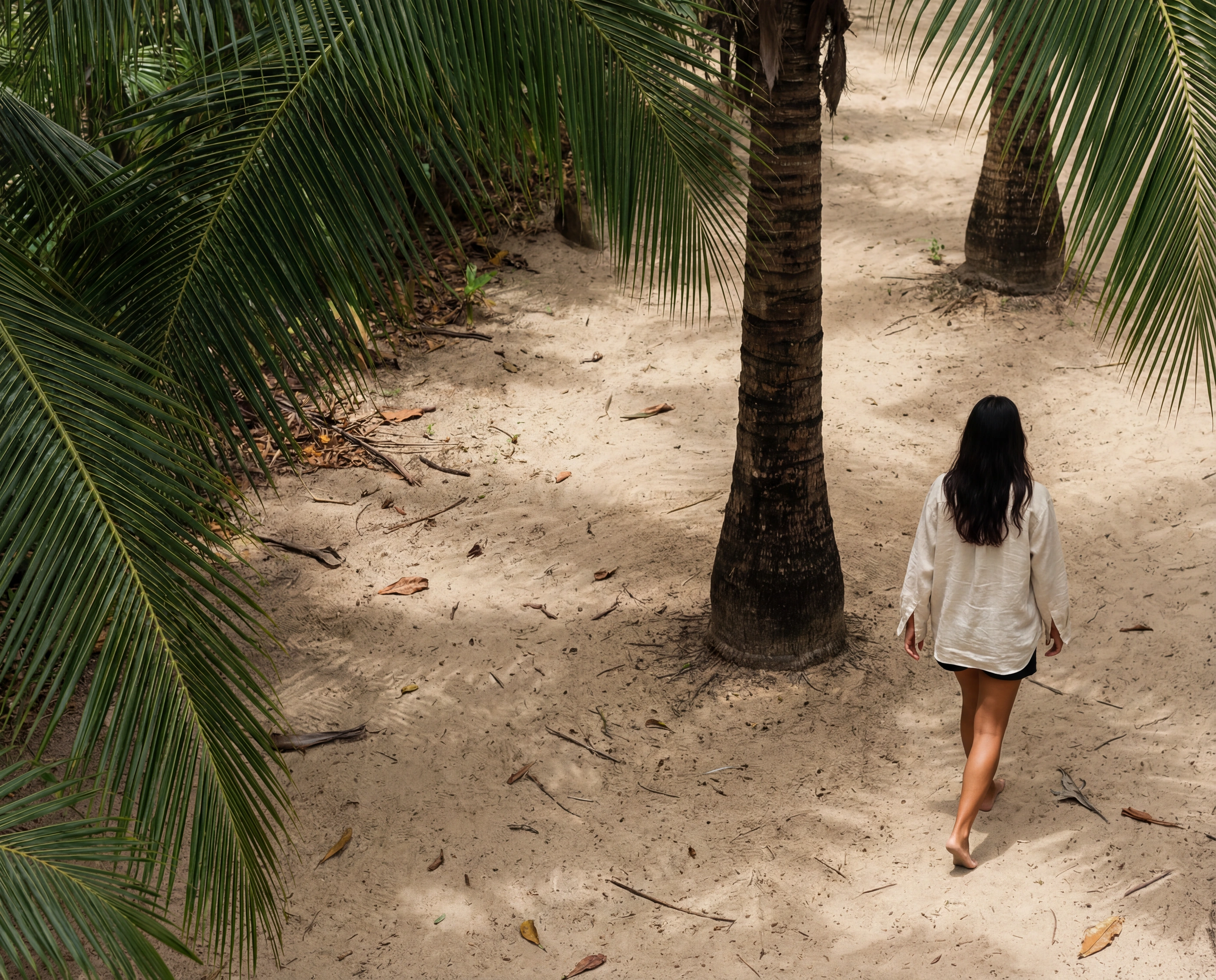 woman walking palm sand path
