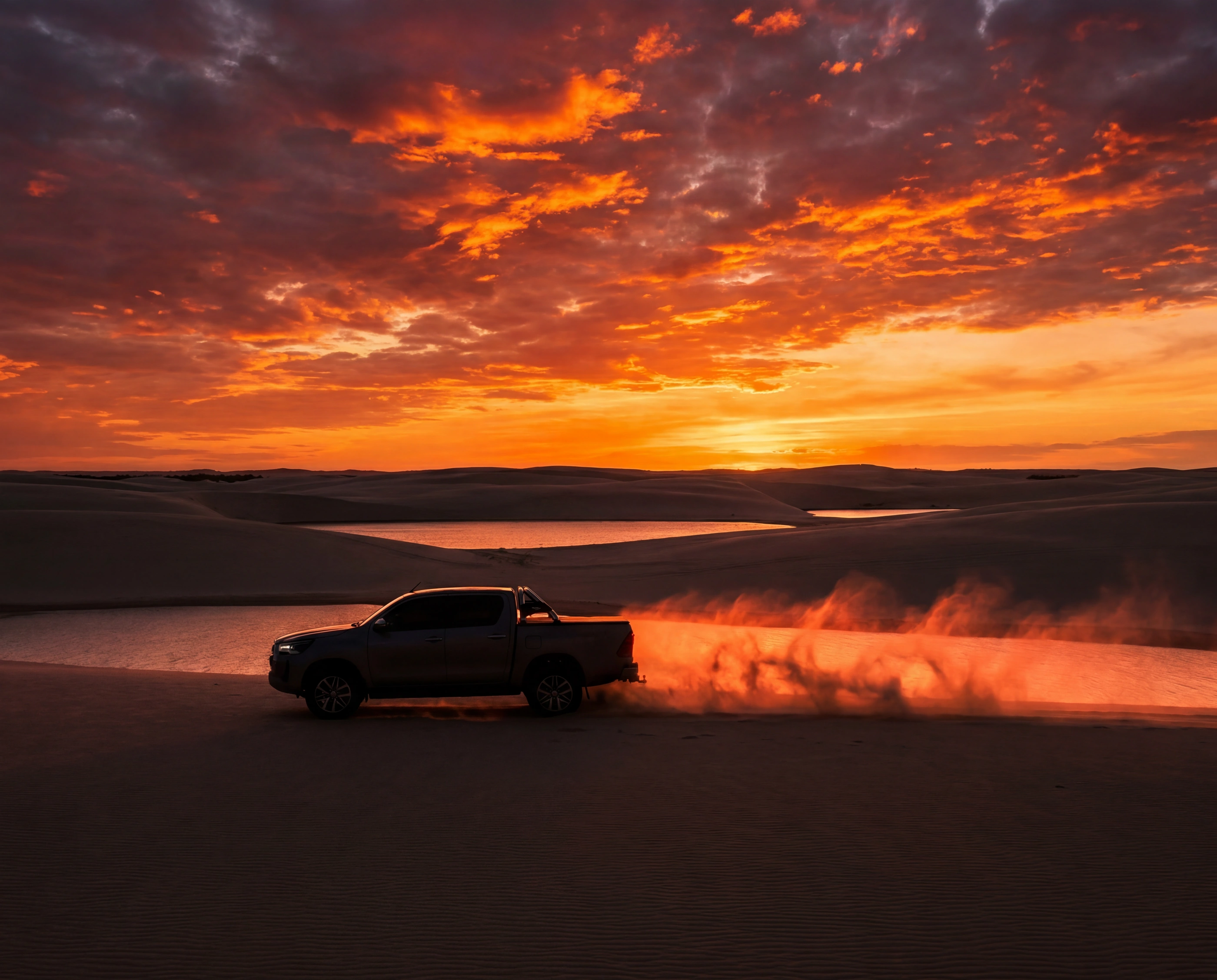 Un 4x4 traversant les dunes au coucher du soleil, soulevant le sable