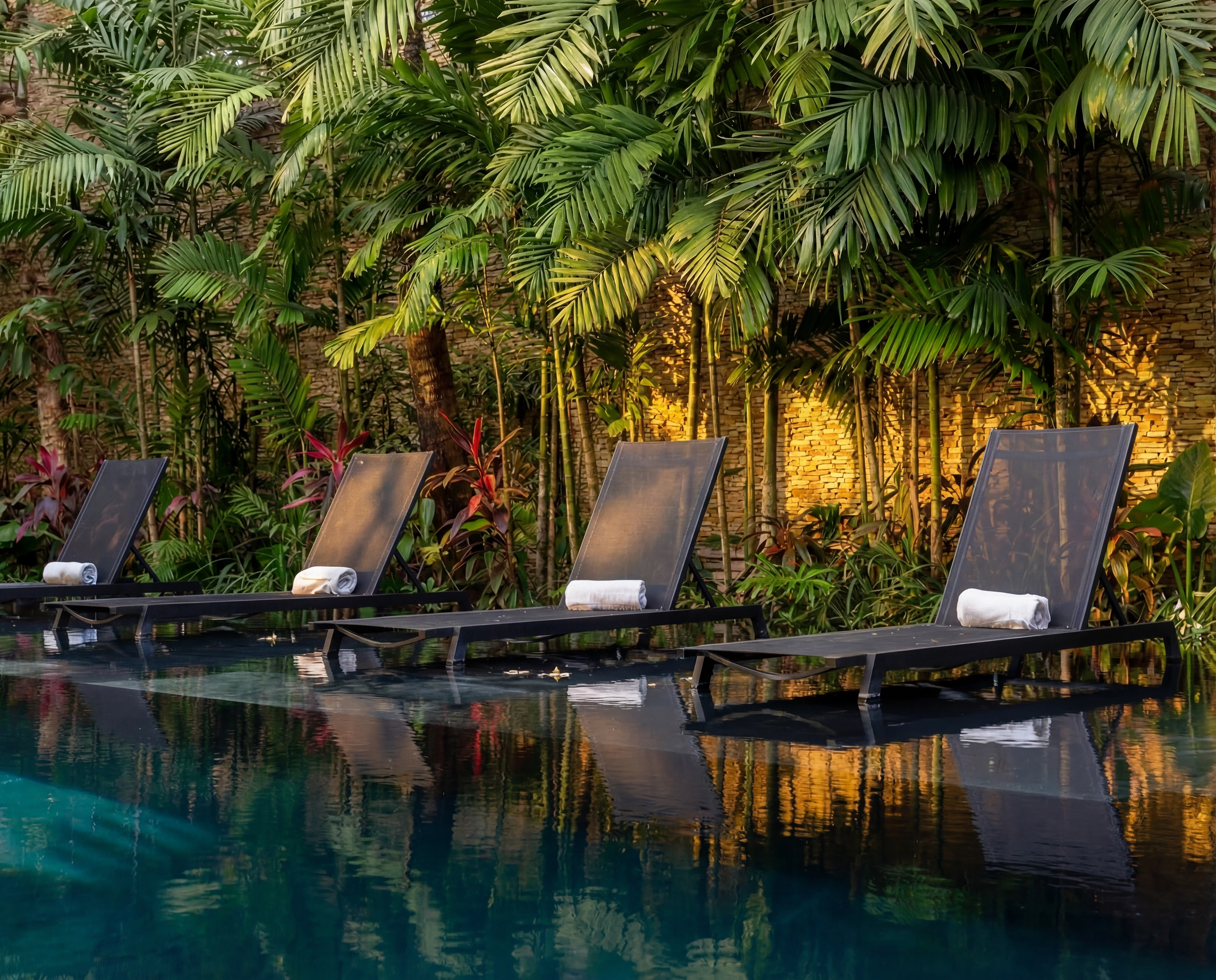 pool loungers palms stone wall