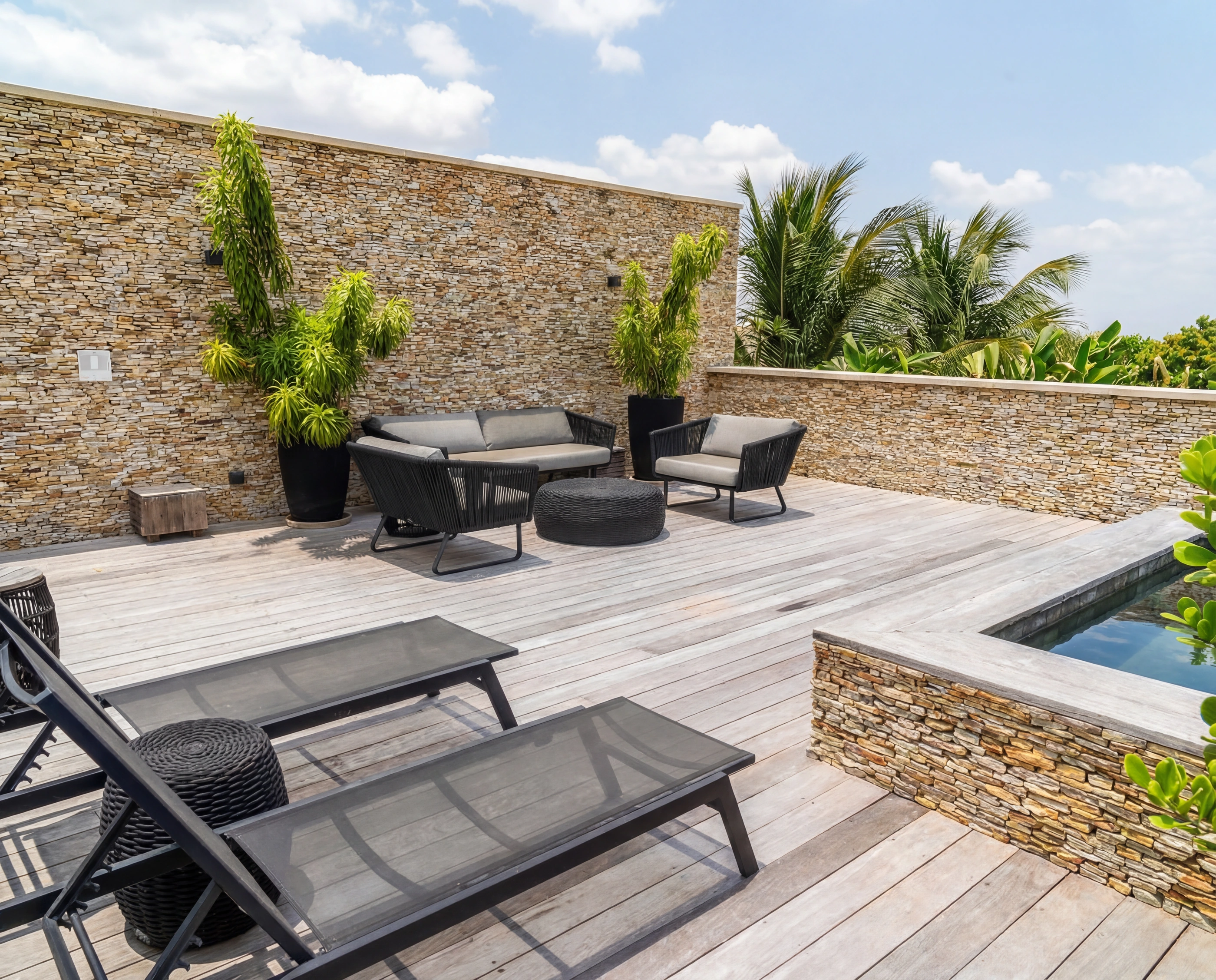 Rooftop loungers beside the private plunge pool, stone planters and distant palms.