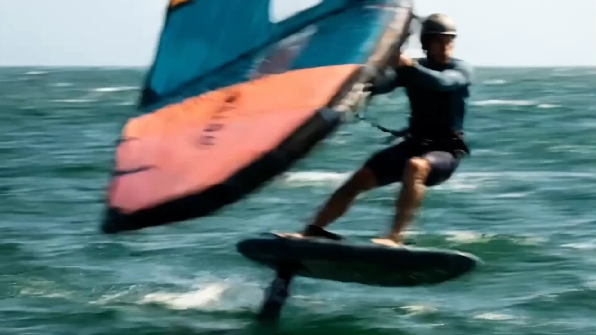 Wing-foiler en plein vol au-dessus de la mer, foil hors de l'eau.